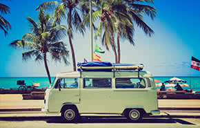 Green old bus on a beach with palms